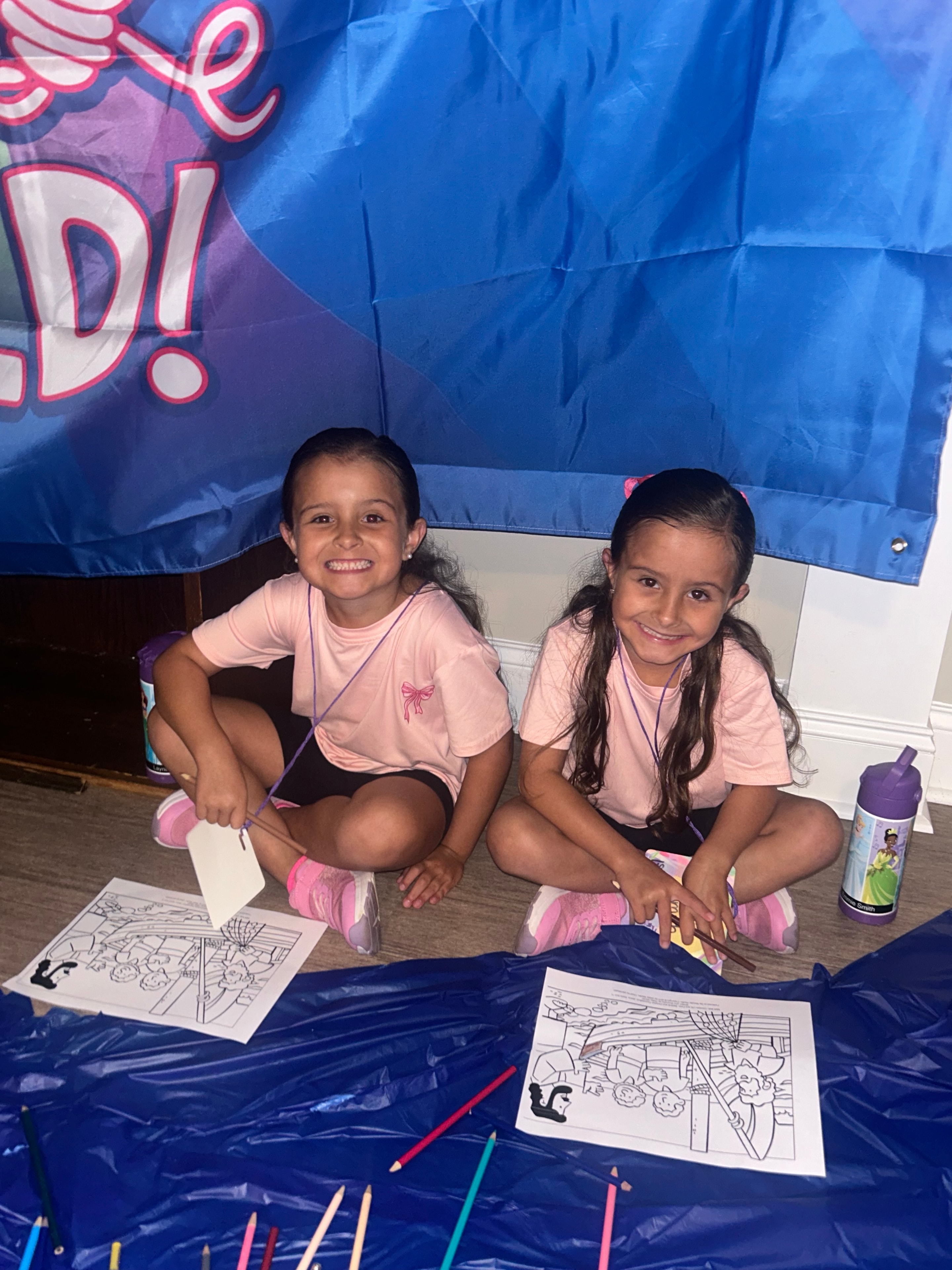 Two girls smiling at the coloring activity table at VBS 2026