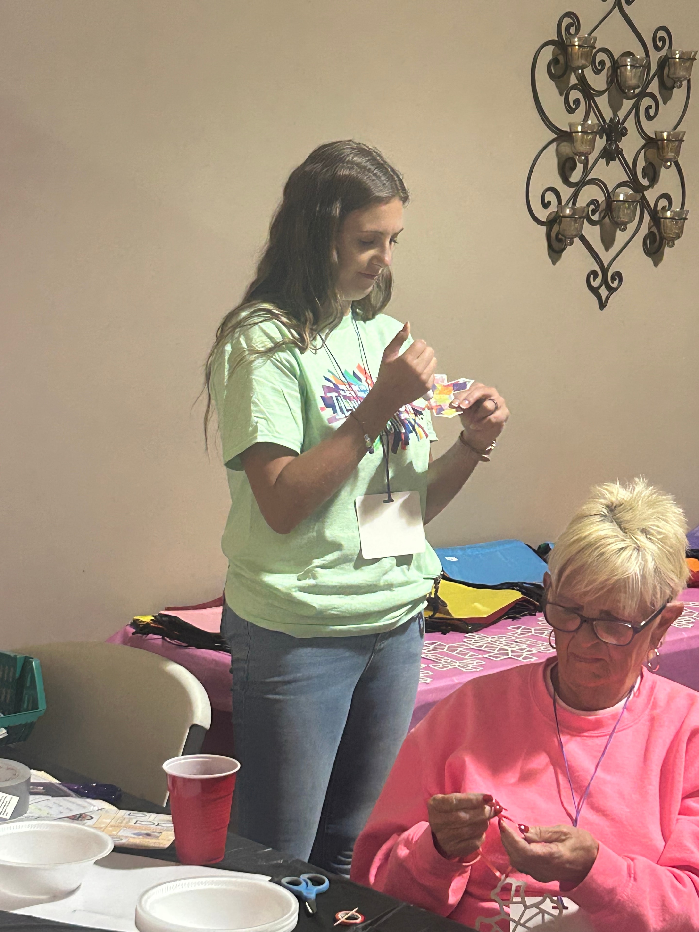 VBS volunteers making craft necklaces at a station