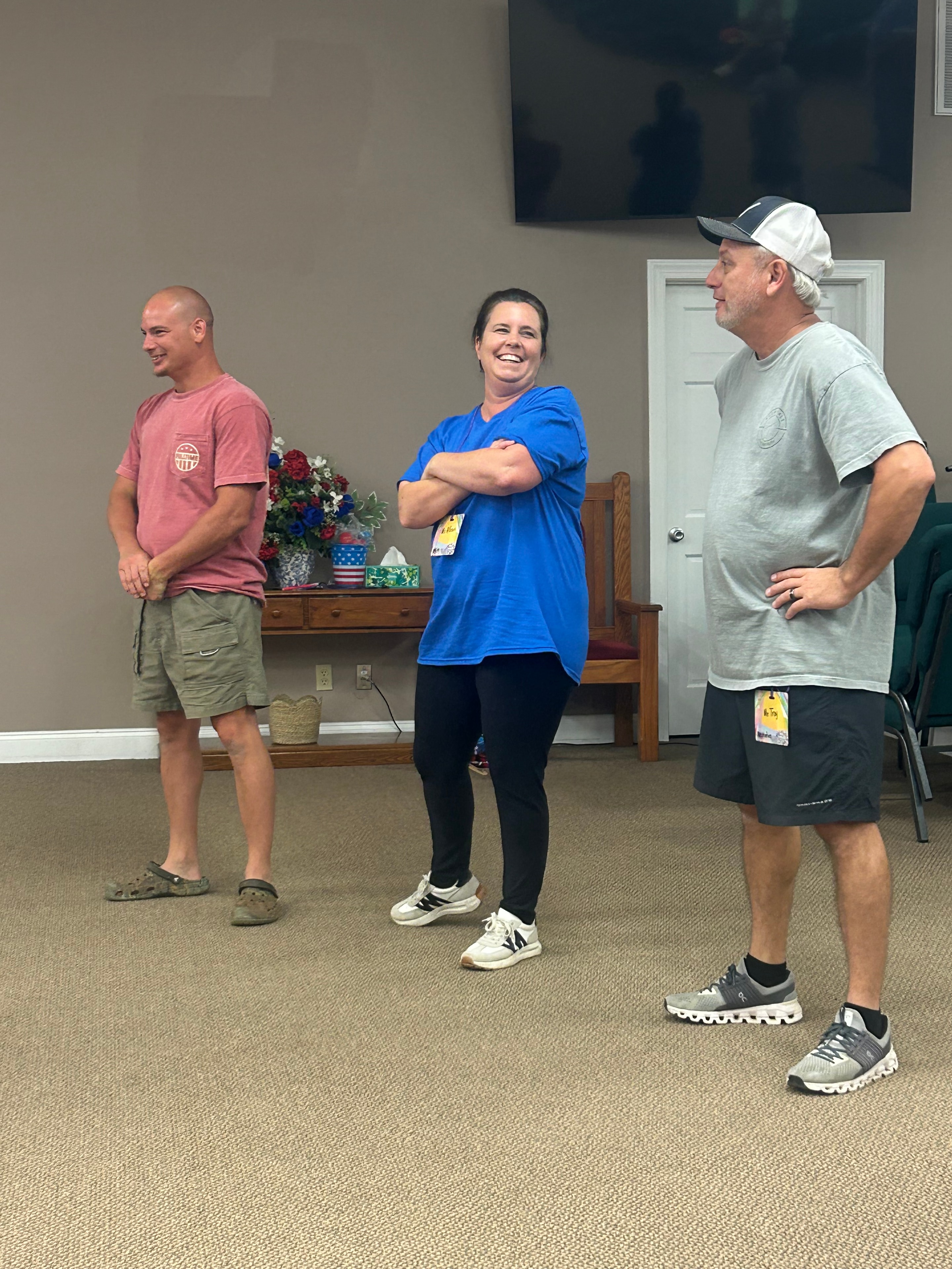Three VBS volunteers smiling together indoors at VBS 2026