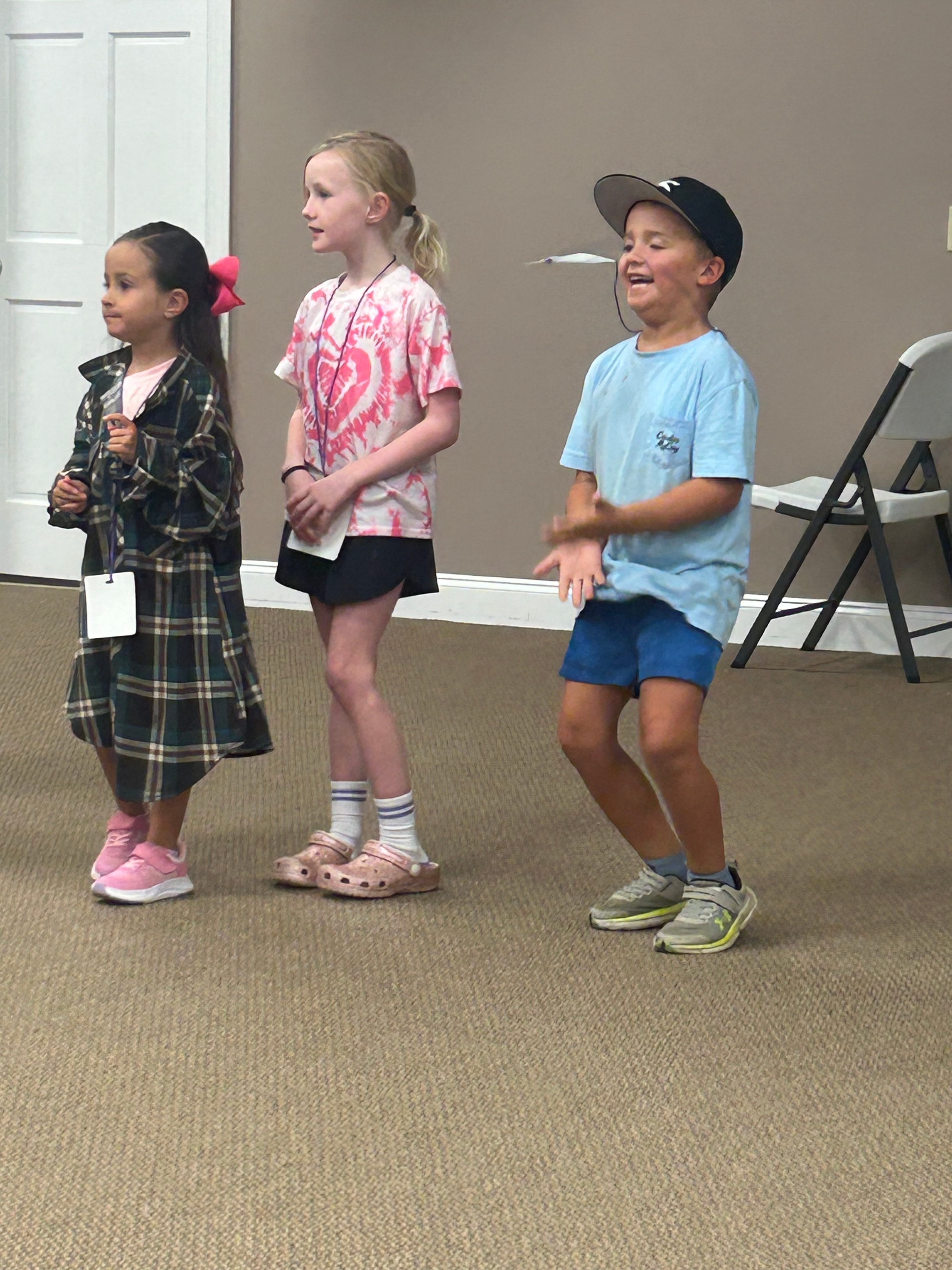 Three children standing together indoors at VBS 2026